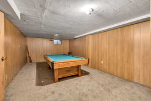 Playroom featuring light colored carpet, billiards table, and wood walls