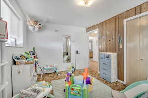 Recreation room featuring wooden walls and baseboards