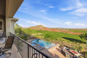 Balcony with view of golf course, a pool with connected hot tub, view of pool, and a mountain view