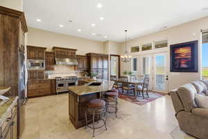 Kitchen featuring light stone countertops, a kitchen island with sink, open floor plan, a kitchen bar, and stainless steel appliances