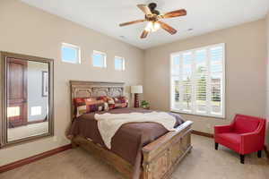 Bedroom featuring ceiling fan, multiple windows, and light colored carpet
