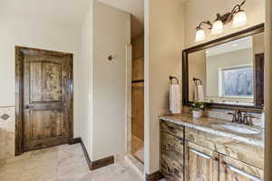 Bathroom featuring a walk in shower, vanity, and light tile patterned flooring