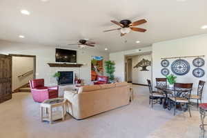 Living area with a ceiling fan, recessed lighting, light carpet, and a tiled fireplace