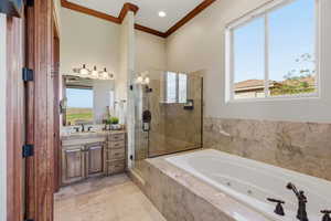 Bathroom with ornamental molding, vanity, a shower stall, healthy amount of natural light, and a jetted tub