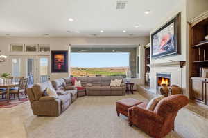 Living area with healthy amount of natural light, a warm lit fireplace, and recessed lighting