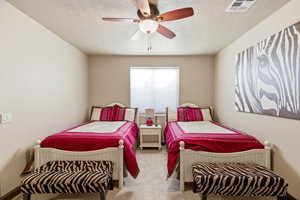 Bedroom featuring a ceiling fan, light carpet, and a textured ceiling
