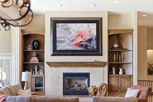 Living room with built in features, a premium fireplace, and recessed lighting