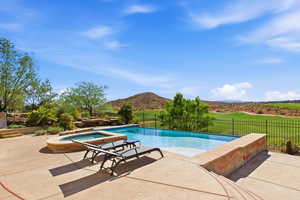 View of pool with patio surround, a fenced backyard, an in-ground hot tub, and a mountain view