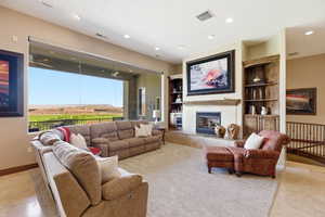 Living room with built in features, a premium fireplace, and recessed lighting