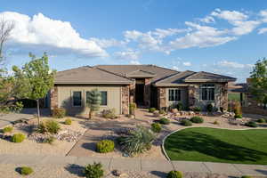 View of front of property with stone siding, a front yard, and stucco siding