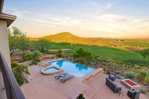 Integrated pool / spa featuring a fenced backyard, a patio, an outdoor living space with a fire pit, and golf course view