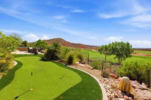 View of home's community with a fenced backyard, a mountain view, an area to practice putting, outdoor furniture, and a patio