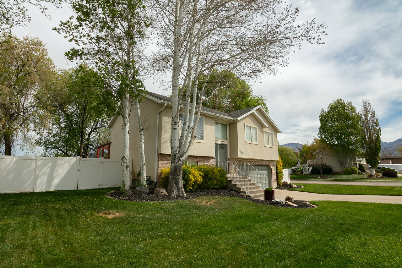 Split foyer home with brick siding, a gate, stucco siding, an attached garage, and driveway