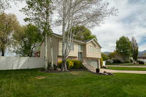 Split foyer home with brick siding, a gate, stucco siding, an attached garage, and driveway