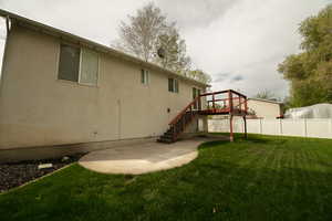 Back of house featuring a patio area, stucco siding, and a wooden deck