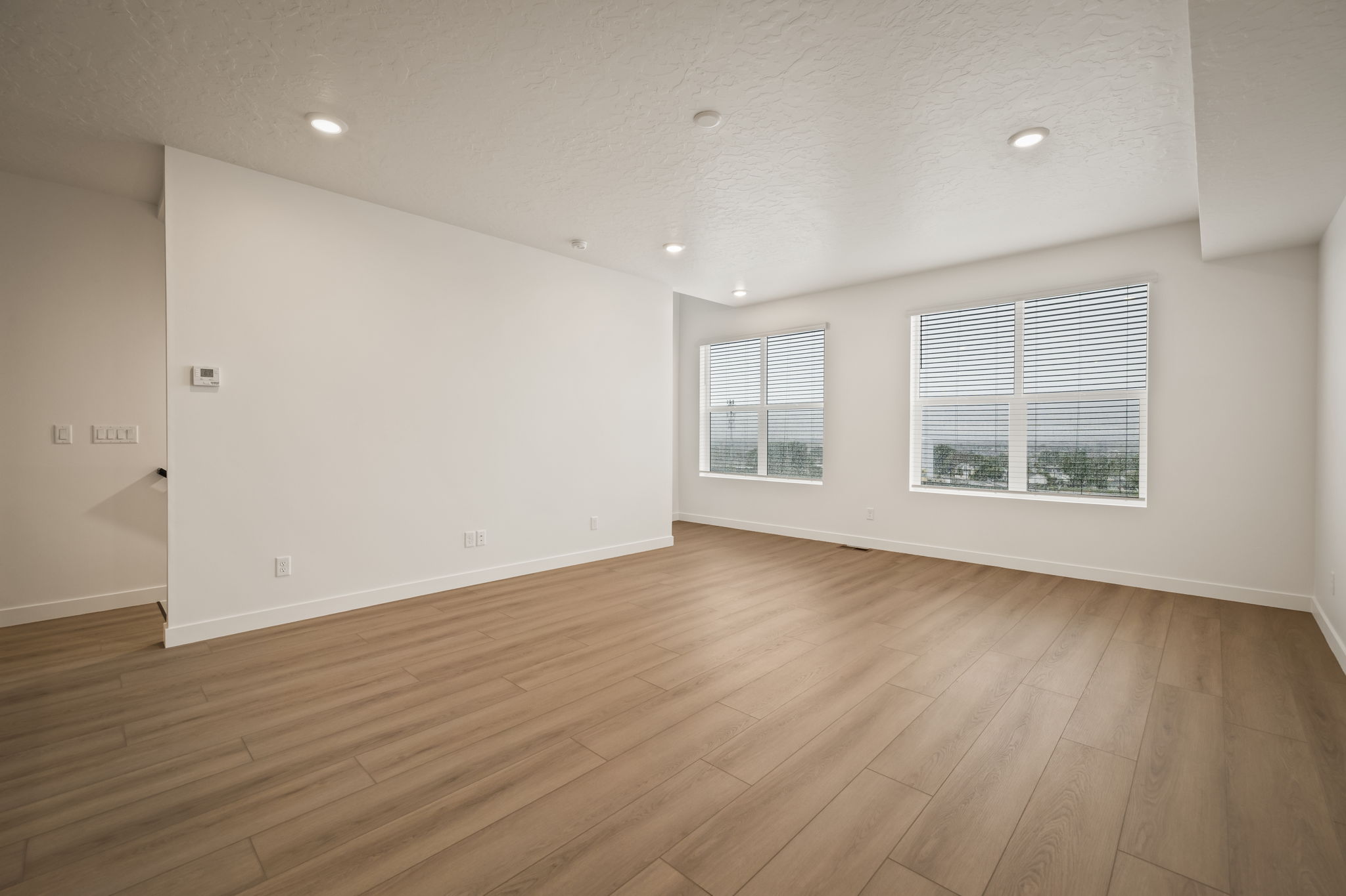 Spacious room featuring wood-finish flooring, recessed lighting, and white walls