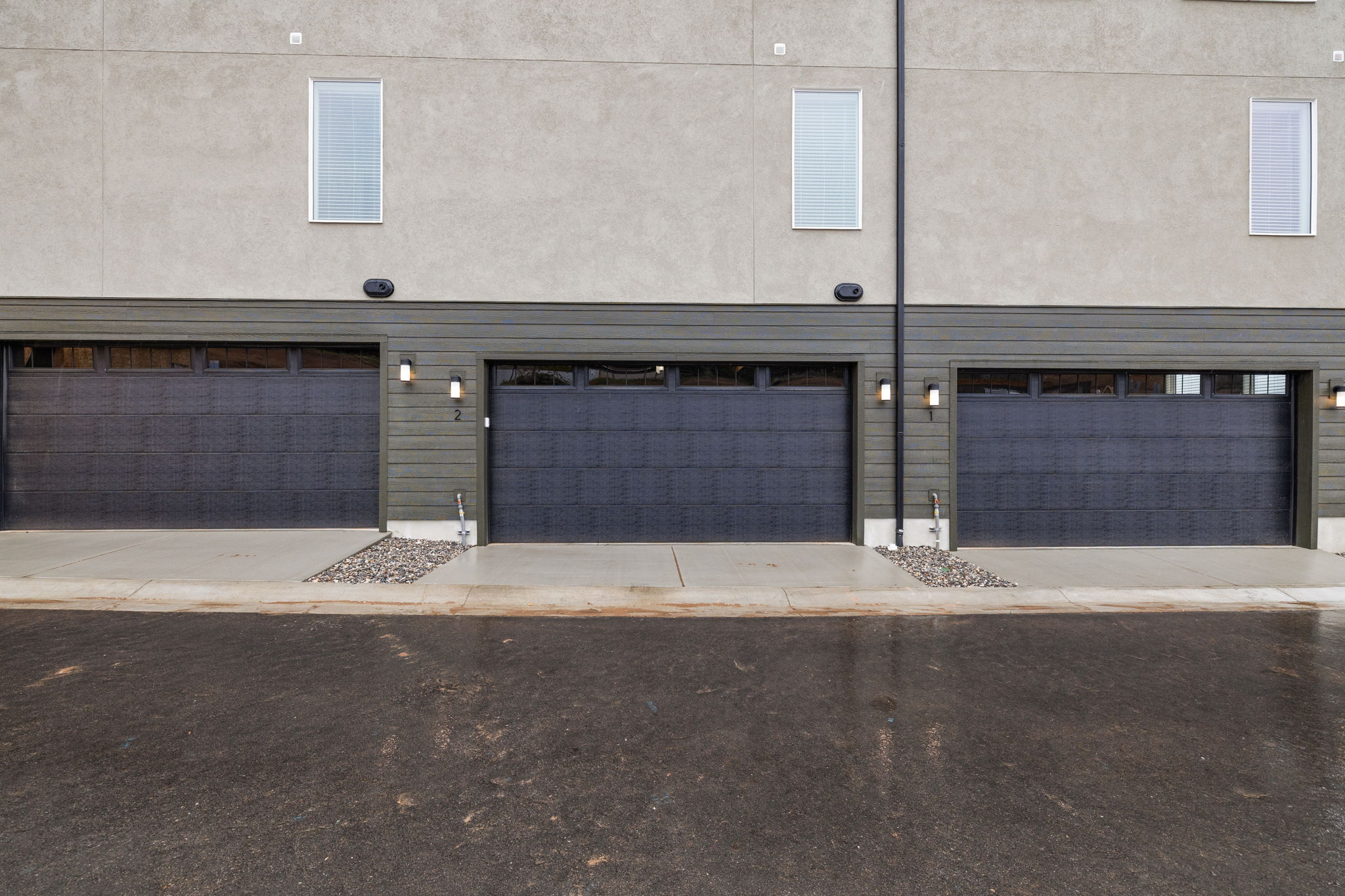 Modern exterior featuring three dark-paneled garage doors with upper window inserts