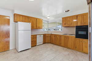 Kitchen featuring white appliances, light countertops, and wood finish cabinets