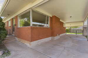 View of home's exterior with brick siding, an attached carport, and a gate