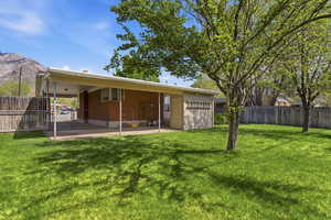Rear view of house with a fenced backyard, a patio area, brick siding, and a mountain view