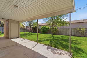 Fenced backyard featuring a patio and a storage unit