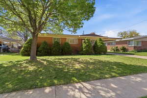 Ranch-style home with a front yard and brick siding