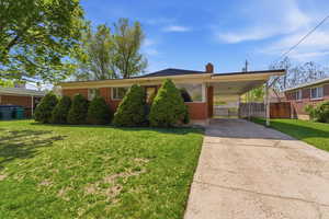 Single story home with brick siding, a chimney, an attached carport, and concrete driveway