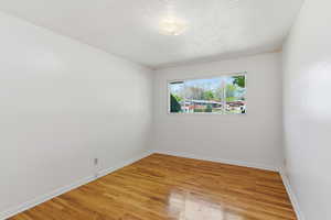 Unfurnished room with light wood finished floors and a textured ceiling