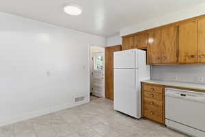 Kitchen featuring light countertops, wood finish cabinetry, and white appliances