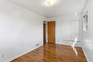 Unfurnished bedroom with wood finished floors and a closet