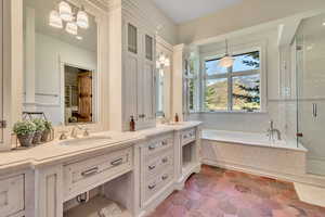Bathroom with double vanity, a bath, a stall shower, and hanging lights