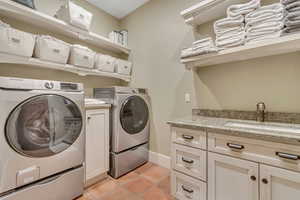 Laundry area featuring separate washer and dryer, cabinet space, and light tile patterned floors