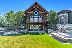 Rear view of property with a lawn, a patio area, stone siding, and french doors