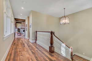 Hall with hardwood / wood-style floors, an upstairs landing, and hanging lights