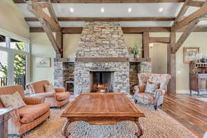Living area featuring a fireplace, beam ceiling, wood finished floors, and recessed lighting