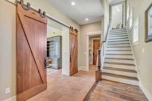 Stairs with a barn door, tile patterned floors, and recessed lighting