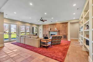 Living room featuring a fireplace, a ceiling fan, recessed lighting, french doors, and light tile patterned floors