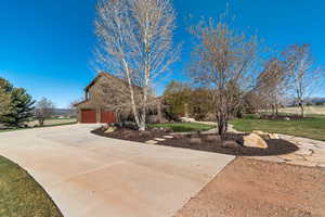 View of front of house with a front lawn, concrete driveway, and a garage