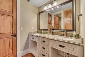 Full bathroom with double vanity and baseboards
