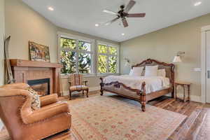 Bedroom with a fireplace, wood-type flooring, recessed lighting, and a ceiling fan