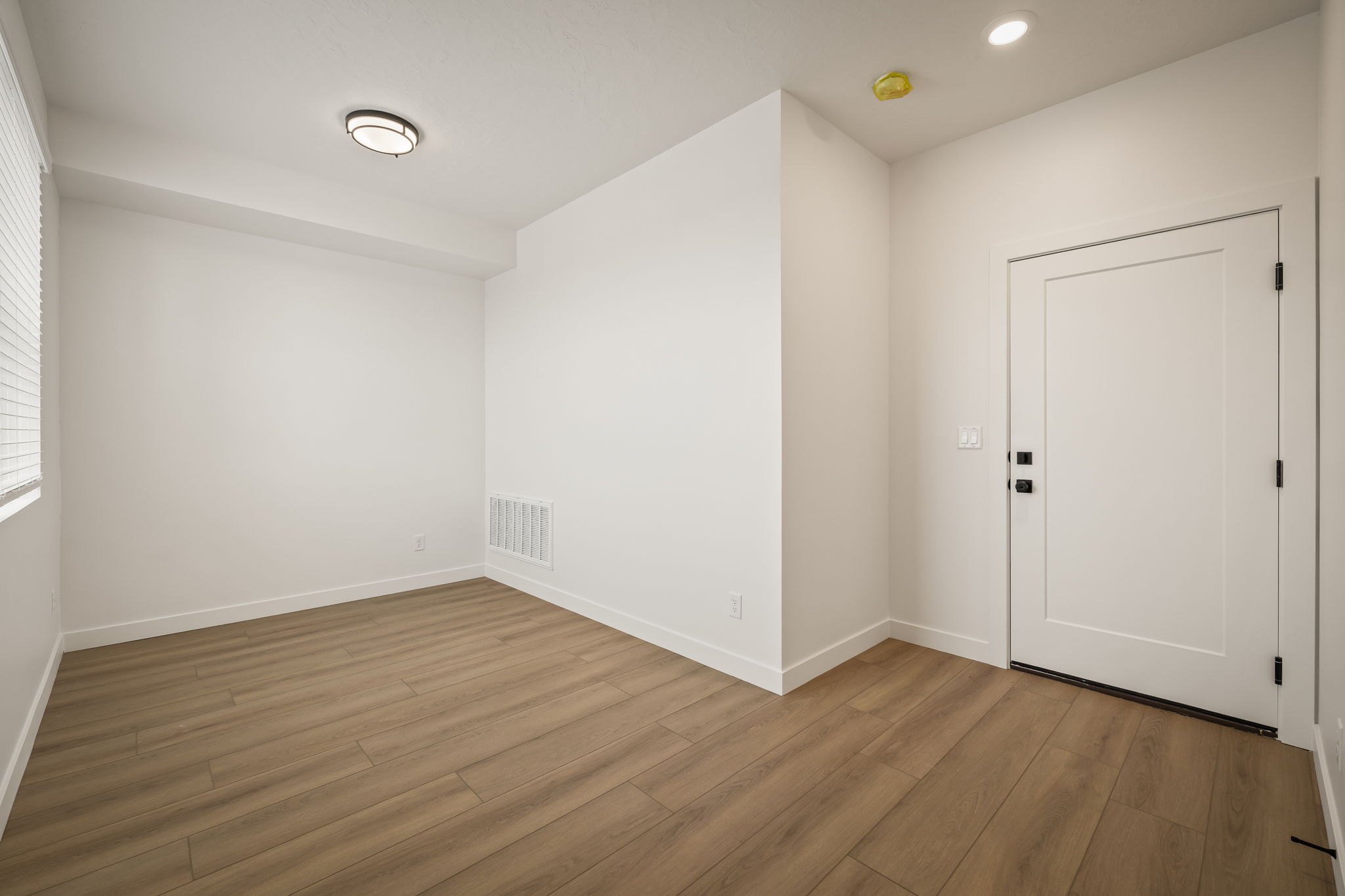 Room featuring light wood-finish flooring, white baseboards, and a window with blinds