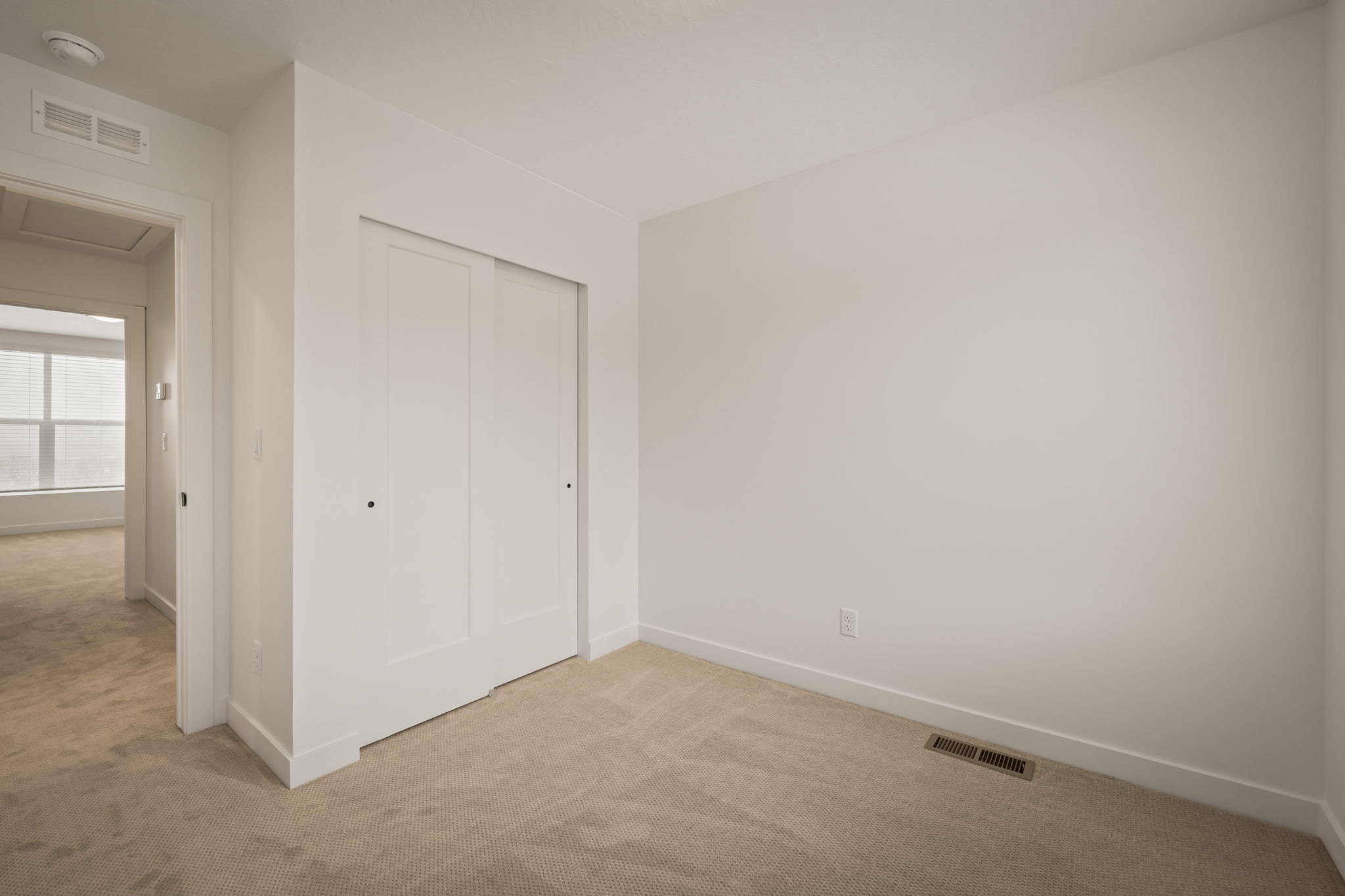 Neutral-toned wall space featuring a full-height, double sliding door closet with flat panel doors and black hardware