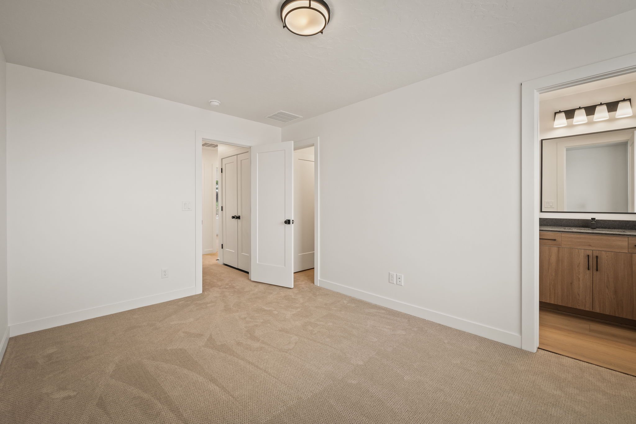 Spacious room with plush carpeting, crisp white walls, and a contemporary ceiling light fixture