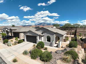 View of front of property with stucco siding, concrete driveway, an attached garage, and a mountain view