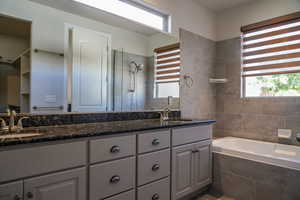 Full bathroom featuring double vanity, a bath, and tiled shower