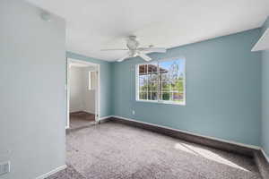 Empty room featuring light colored carpet and a ceiling fan