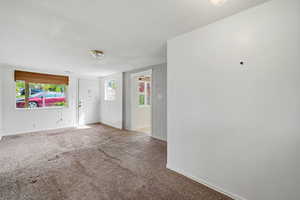 Carpeted spare room featuring baseboards