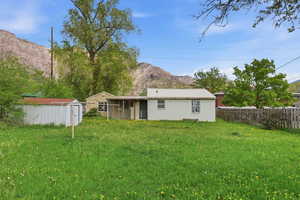 Back of house featuring a shed, a metal roof, a mountain view, and a lawn