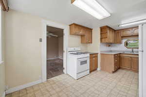 Kitchen featuring white appliances, light countertops, wood finish cabinetry, and light carpet