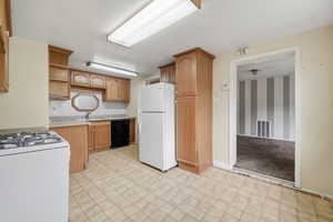 Kitchen with light countertops, white appliances, open shelves, light flooring, and decorative backsplash